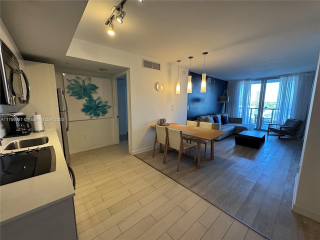 dining area featuring light wood finished floors, rail lighting, visible vents, and baseboards