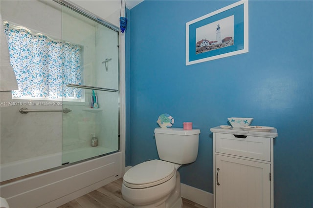 full bathroom with enclosed tub / shower combo, wood finished floors, toilet, and baseboards