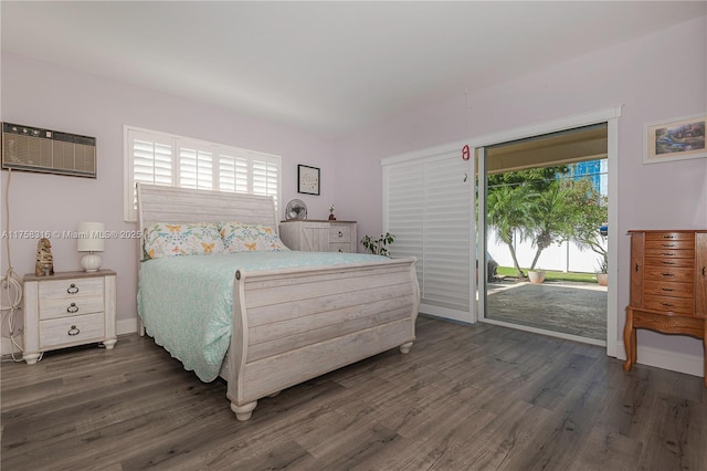 bedroom with access to exterior, dark wood-style flooring, an AC wall unit, and baseboards