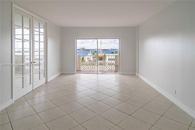 empty room featuring french doors, baseboards, and light tile patterned floors