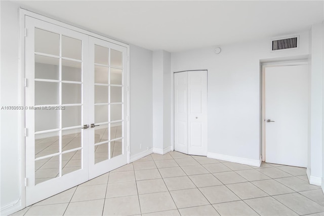 unfurnished bedroom featuring light tile patterned floors, baseboards, visible vents, french doors, and a closet