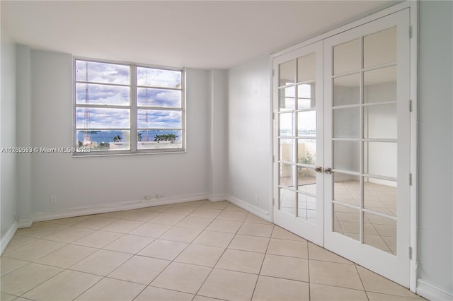 spare room featuring light tile patterned floors, baseboards, and french doors