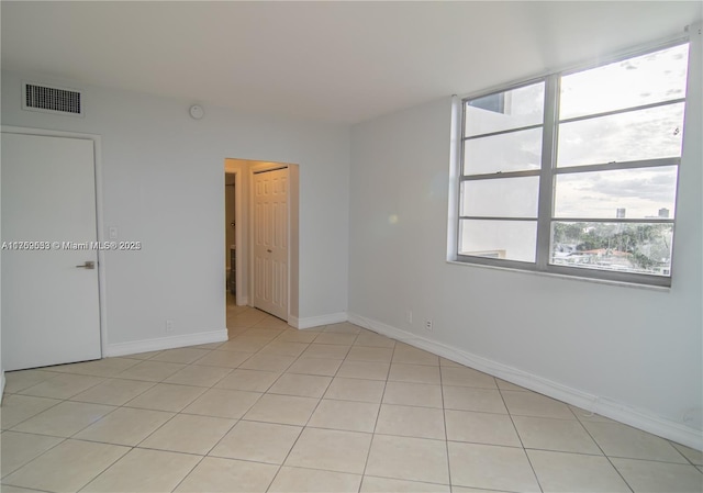 empty room with visible vents, baseboards, and light tile patterned floors