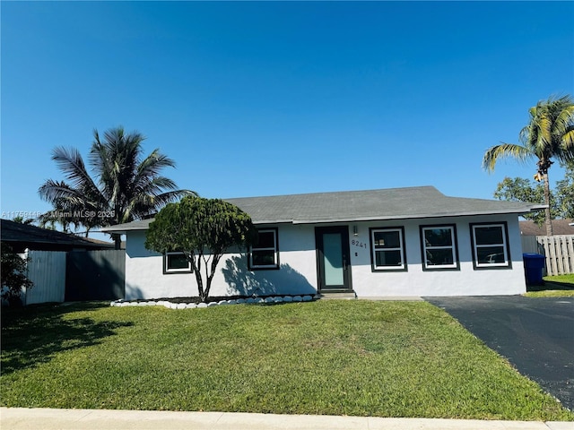 single story home with aphalt driveway, fence, a front lawn, and stucco siding