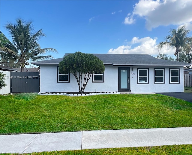 ranch-style house featuring a front lawn, fence, and stucco siding