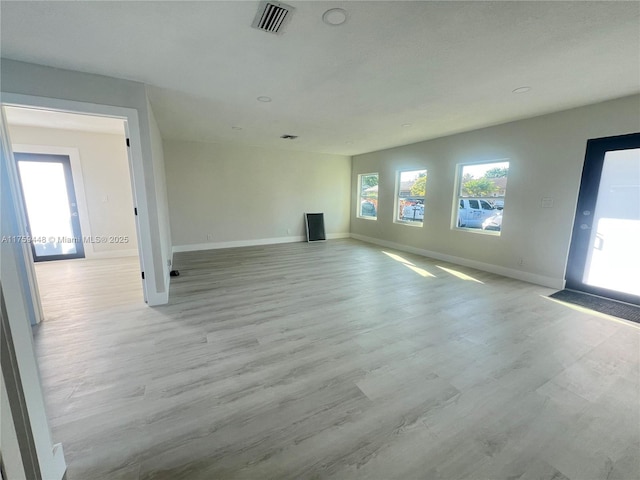 unfurnished living room featuring baseboards, visible vents, and light wood-type flooring