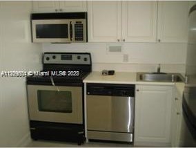 kitchen featuring white cabinets, appliances with stainless steel finishes, light countertops, and a sink