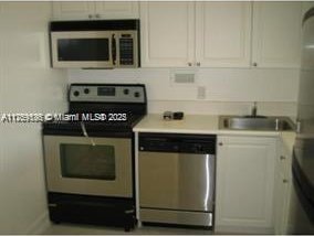 1455 N Treasure Dr Unit 7L, North Bay Village, FL 33141 - kitchen with light countertops, appliances with stainless steel finishes, a sink, and white cabinetry