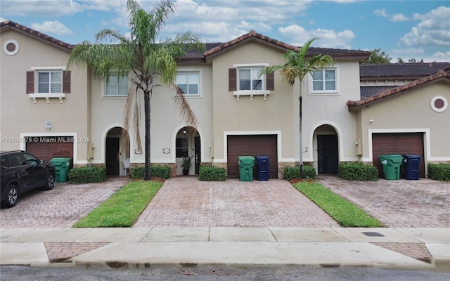 multi unit property with stone siding, decorative driveway, and stucco siding