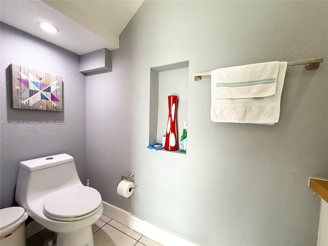 half bath featuring toilet, tile patterned flooring, and baseboards