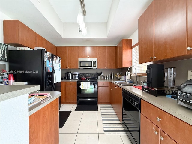 kitchen featuring light tile patterned floors, a raised ceiling, brown cabinets, black appliances, and a sink