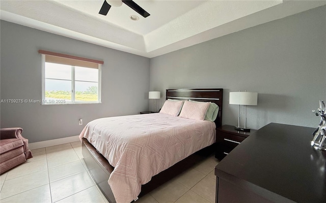 bedroom featuring a ceiling fan, a raised ceiling, light tile patterned flooring, and baseboards