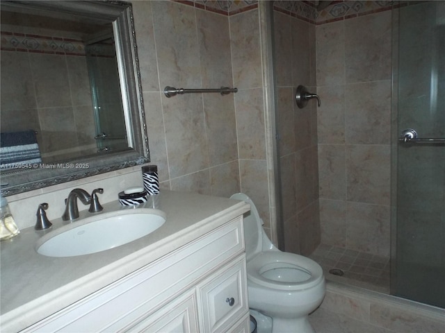 full bath featuring a shower stall, vanity, toilet, and tile walls