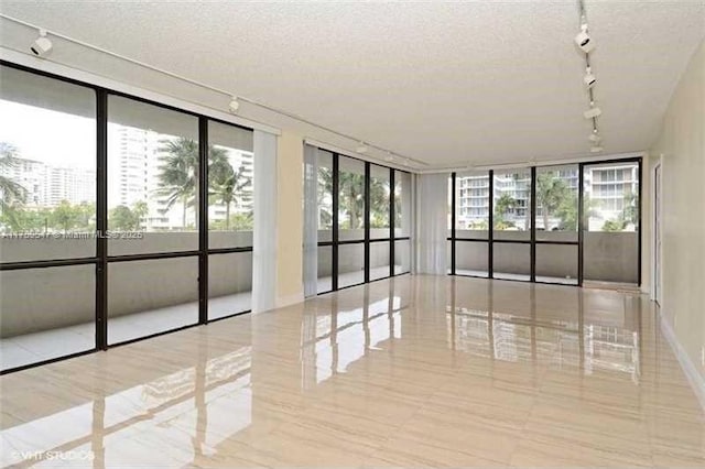 spare room with track lighting, floor to ceiling windows, and a textured ceiling