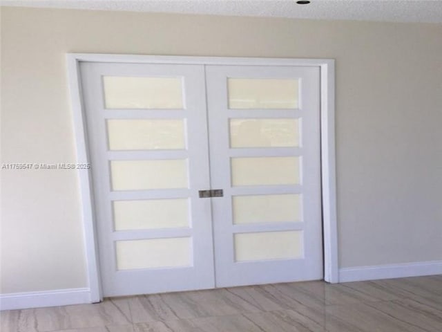 doorway to outside featuring french doors, a textured ceiling, and baseboards