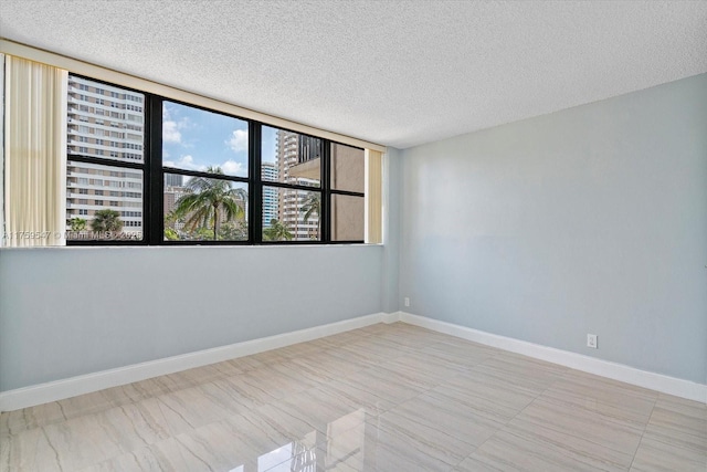 unfurnished room featuring baseboards and a textured ceiling