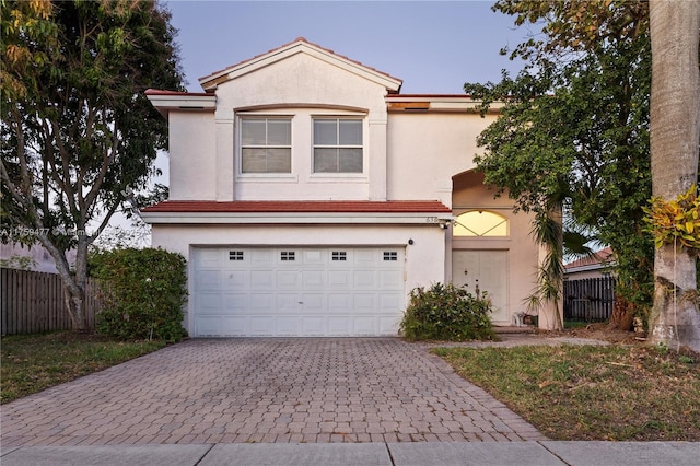 view of front of house featuring a garage, fence, decorative driveway, and stucco siding