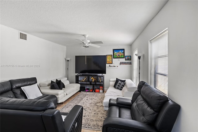 living area featuring visible vents, ceiling fan, a textured ceiling, and wood finished floors