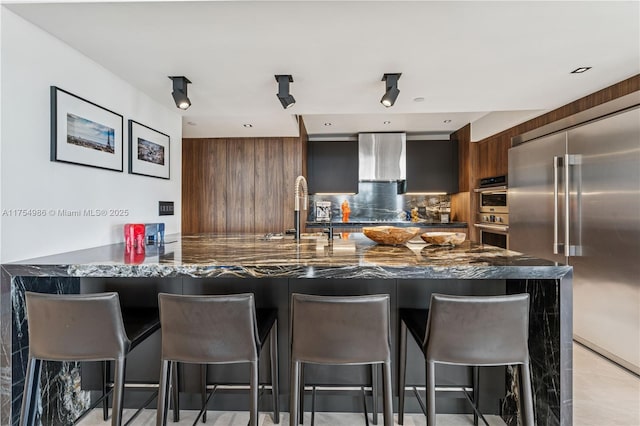 19667 Turnberry Way Unit 8K, Aventura, FL 33180 - kitchen with tasteful backsplash, modern cabinets, wall chimney range hood, a breakfast bar, and stainless steel appliances