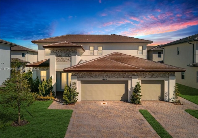 view of front of house featuring a lawn, a tiled roof, decorative driveway, and a garage