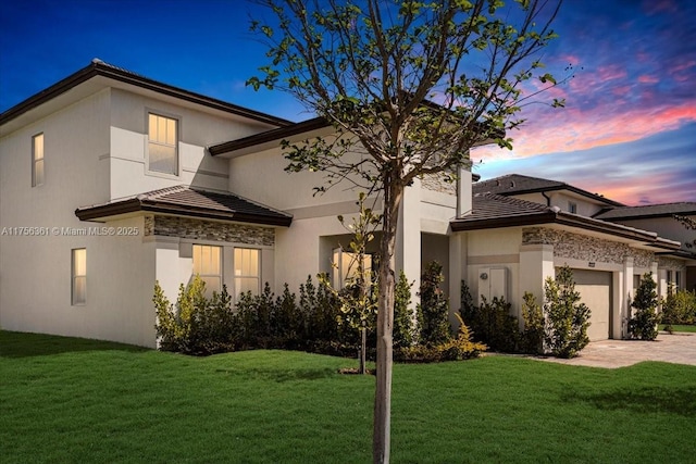 view of front of home featuring a front yard, stucco siding, a garage, a tiled roof, and decorative driveway