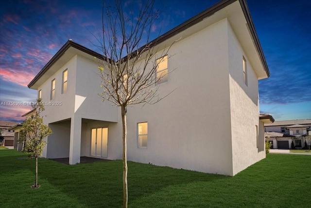 rear view of property with a yard and stucco siding