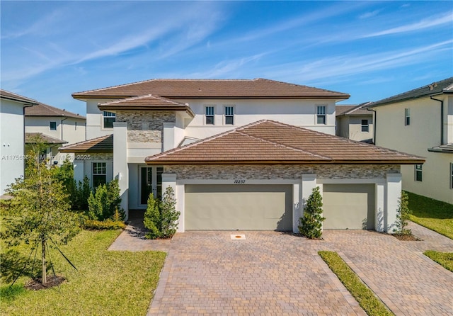 view of front of home featuring decorative driveway, stucco siding, an attached garage, and a tiled roof