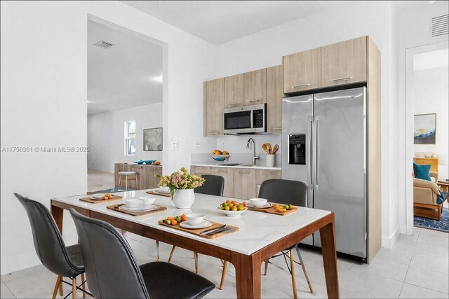 kitchen with light brown cabinets, visible vents, a sink, light countertops, and appliances with stainless steel finishes