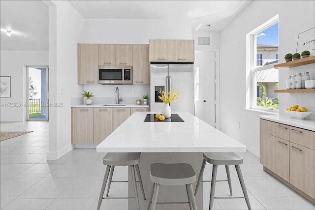 kitchen with a sink, light countertops, light brown cabinets, and stainless steel appliances