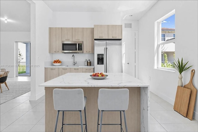 kitchen featuring visible vents, a breakfast bar area, stainless steel appliances, and a sink