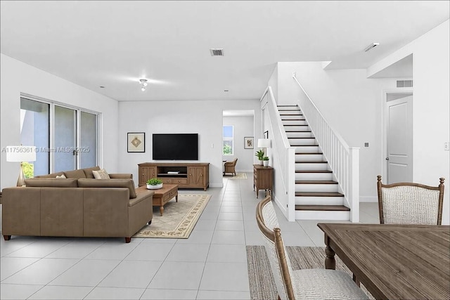 living area featuring light tile patterned floors, visible vents, stairs, and baseboards