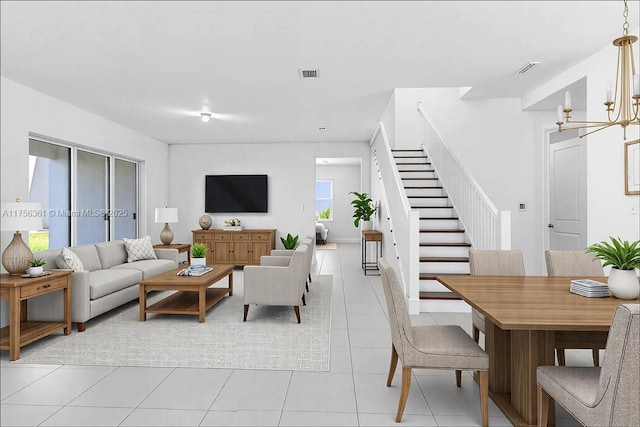 living area featuring stairs, a notable chandelier, light tile patterned floors, and visible vents