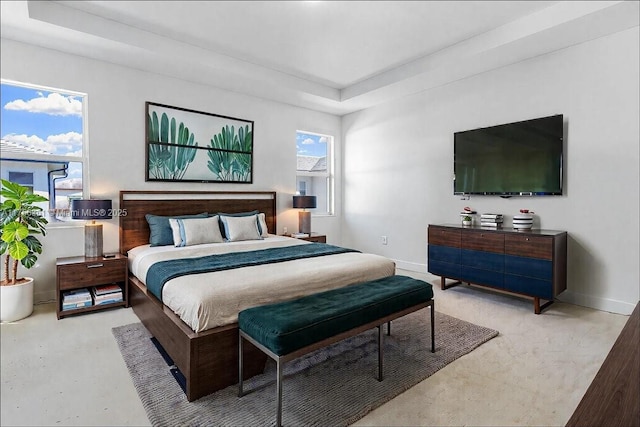 bedroom featuring a tray ceiling and baseboards