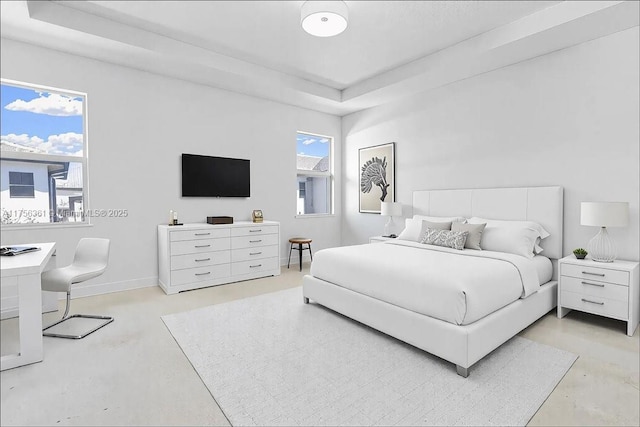 bedroom with a tray ceiling, baseboards, and concrete flooring