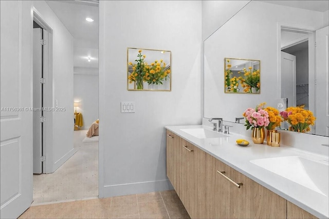 bathroom with tile patterned flooring, double vanity, baseboards, and a sink