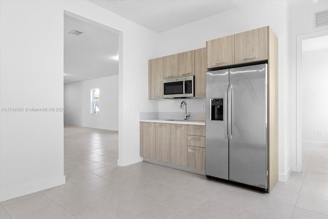 kitchen with light brown cabinets, visible vents, a sink, light countertops, and appliances with stainless steel finishes