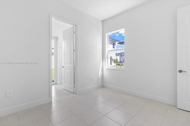 empty room featuring baseboards and light tile patterned flooring