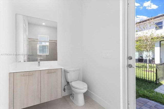 bathroom featuring tile patterned floors, toilet, a healthy amount of sunlight, and vanity