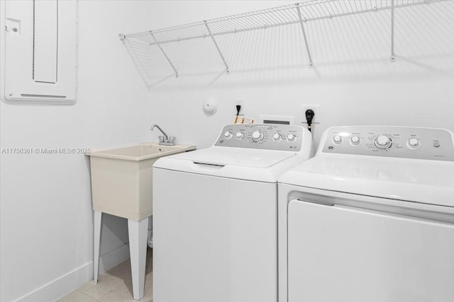 clothes washing area with light tile patterned floors, laundry area, washer and dryer, and baseboards