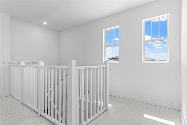 hallway featuring an upstairs landing, recessed lighting, a healthy amount of sunlight, and baseboards