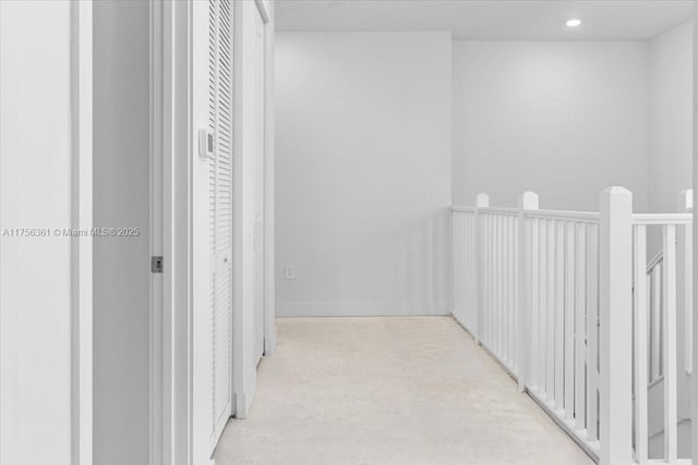 hall featuring recessed lighting, an upstairs landing, and concrete floors