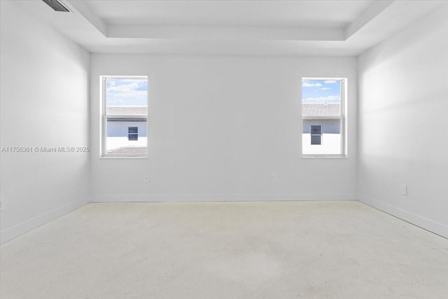 empty room featuring a healthy amount of sunlight, baseboards, concrete flooring, and a tray ceiling