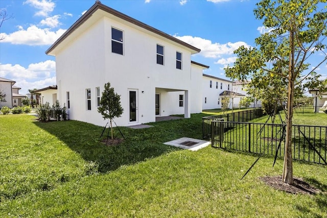 rear view of house featuring stucco siding, fence private yard, and a lawn