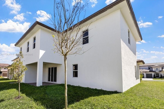 rear view of property featuring stucco siding and a lawn