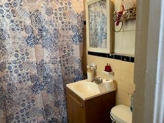 2156 NW 32nd St, Miami, FL 33142 - bathroom featuring toilet, tile walls, and vanity