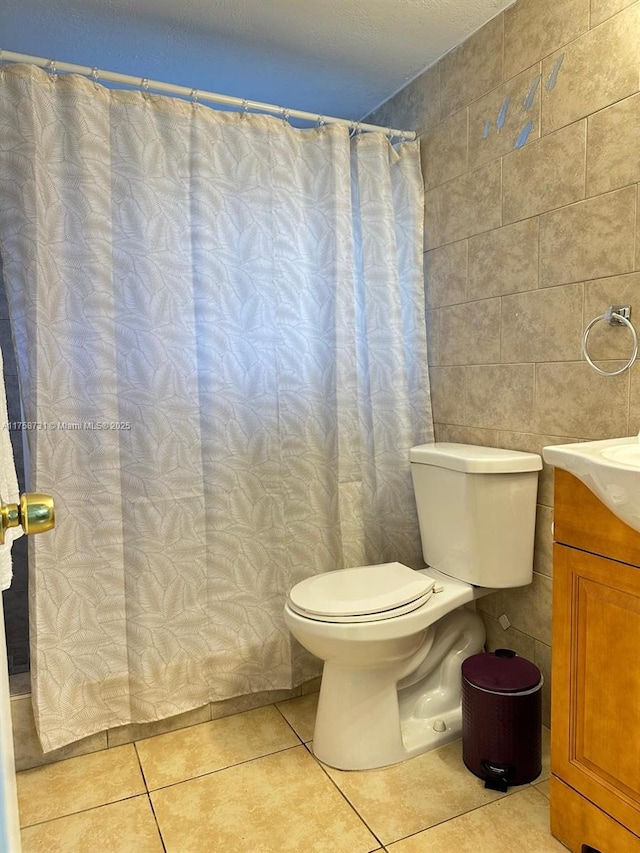 full bathroom with tile patterned floors, toilet, tile walls, and vanity