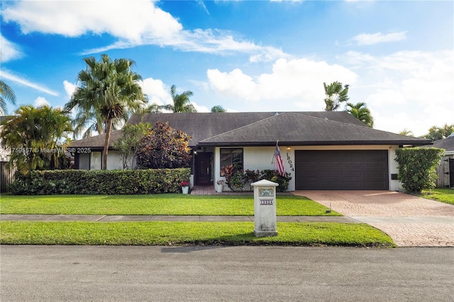 view of front of property featuring a front yard, roof with shingles, driveway, an attached garage, and stucco siding