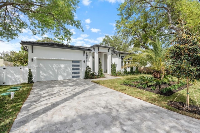 view of front of home featuring an attached garage, fence, driveway, and stucco siding