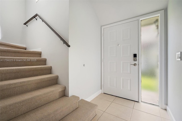 entryway with light tile patterned flooring, stairs, and baseboards