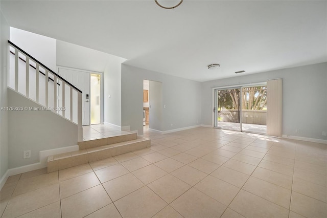 unfurnished living room featuring tile patterned floors, visible vents, baseboards, and stairs